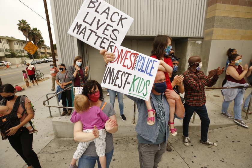 Tony Castello, with his wife, Devon Harlow, hold their daughters Adife, 5, and Niamh, 2, during a June 2020 protest by students activists and community members to urge L.A. Unified School District to defund school police and eliminate their budget. (Al Seib / Los Angeles Times)