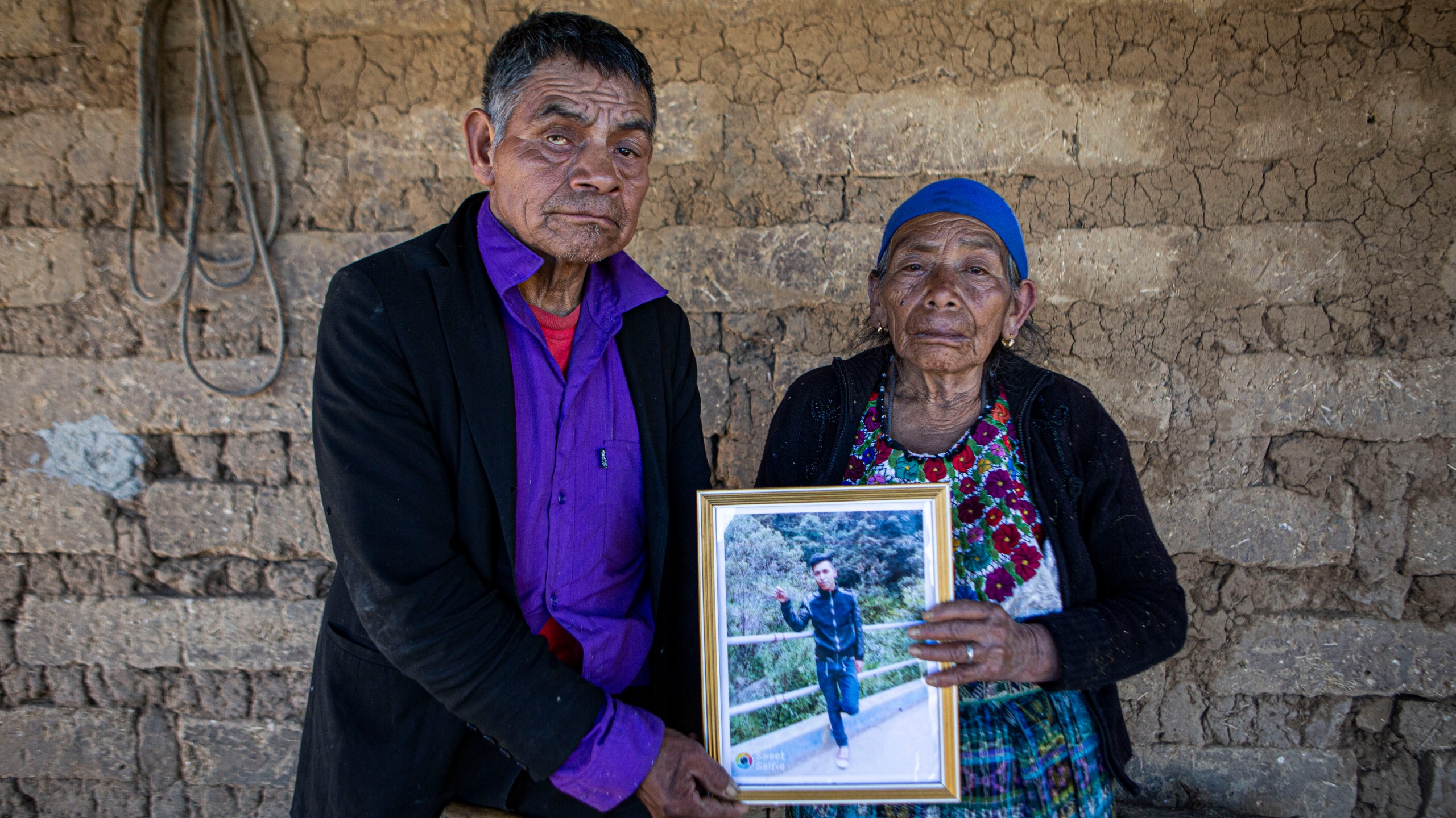 German and Maria Tomas pose for a photograph holding a framed portrait of their grandson Ivan Gudiel, at their home in Comitancillo, Guatemala, Wednesday, Jan. 27, 2021. They believe their grandson is one of the 13 of the 19 charred corpses found in a northern Mexico border state on Saturday. The country's Foreign Ministry said it was collecting DNA samples from a dozen relatives to see if there was a match with any of the bodies. (AP Photo/Oliver de Ros)