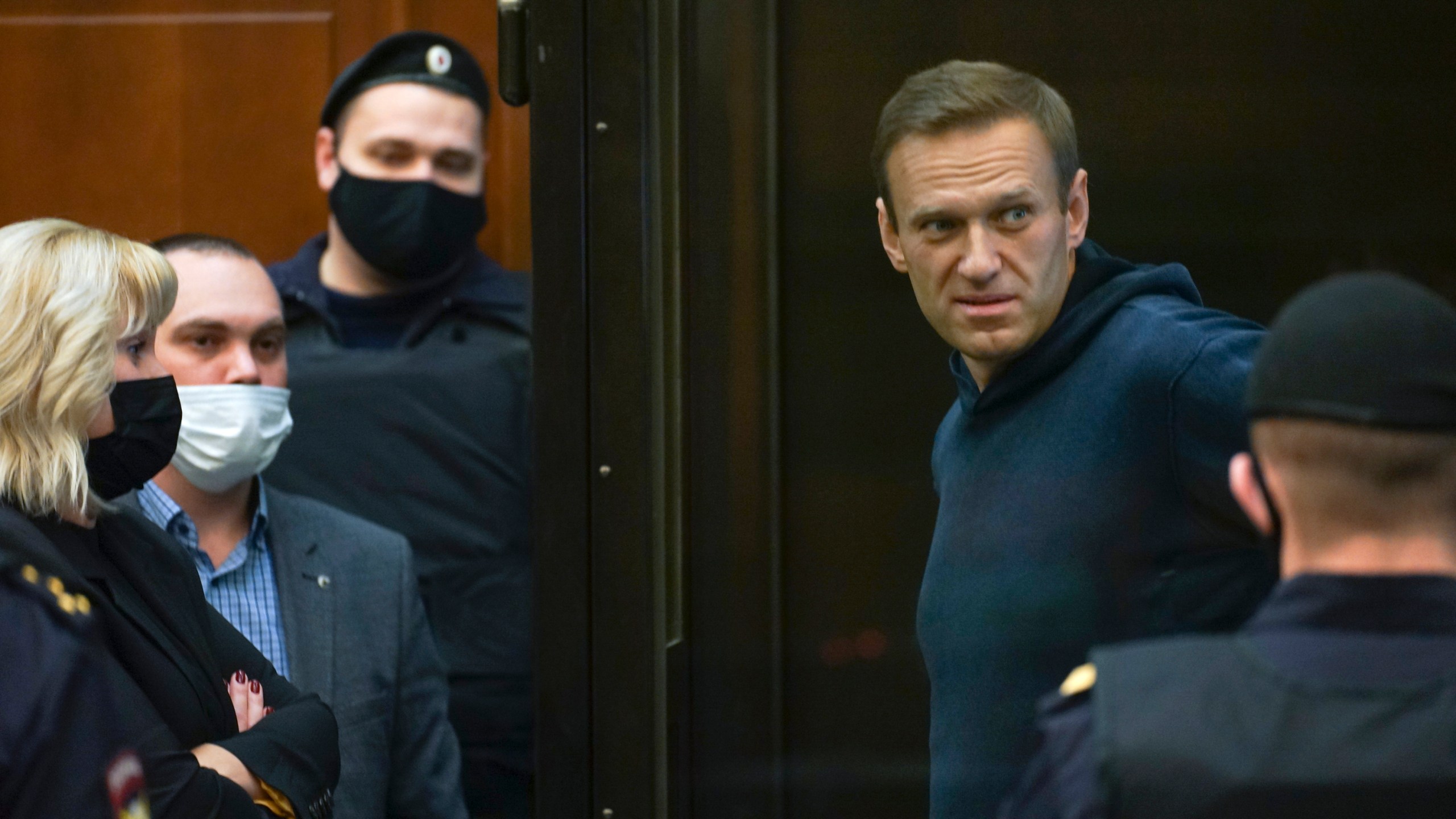 In this handout photo provided by Moscow City Court Russian opposition leader Alexei Navalny talks to his lawyers while standing in a cage during a hearing to a motion from the Russian prison service to convert the suspended sentence of Navalny from the 2014 criminal conviction into a real prison term in the Moscow City Court in Moscow on Feb. 2, 2021. (Moscow City Court via Associated Press)