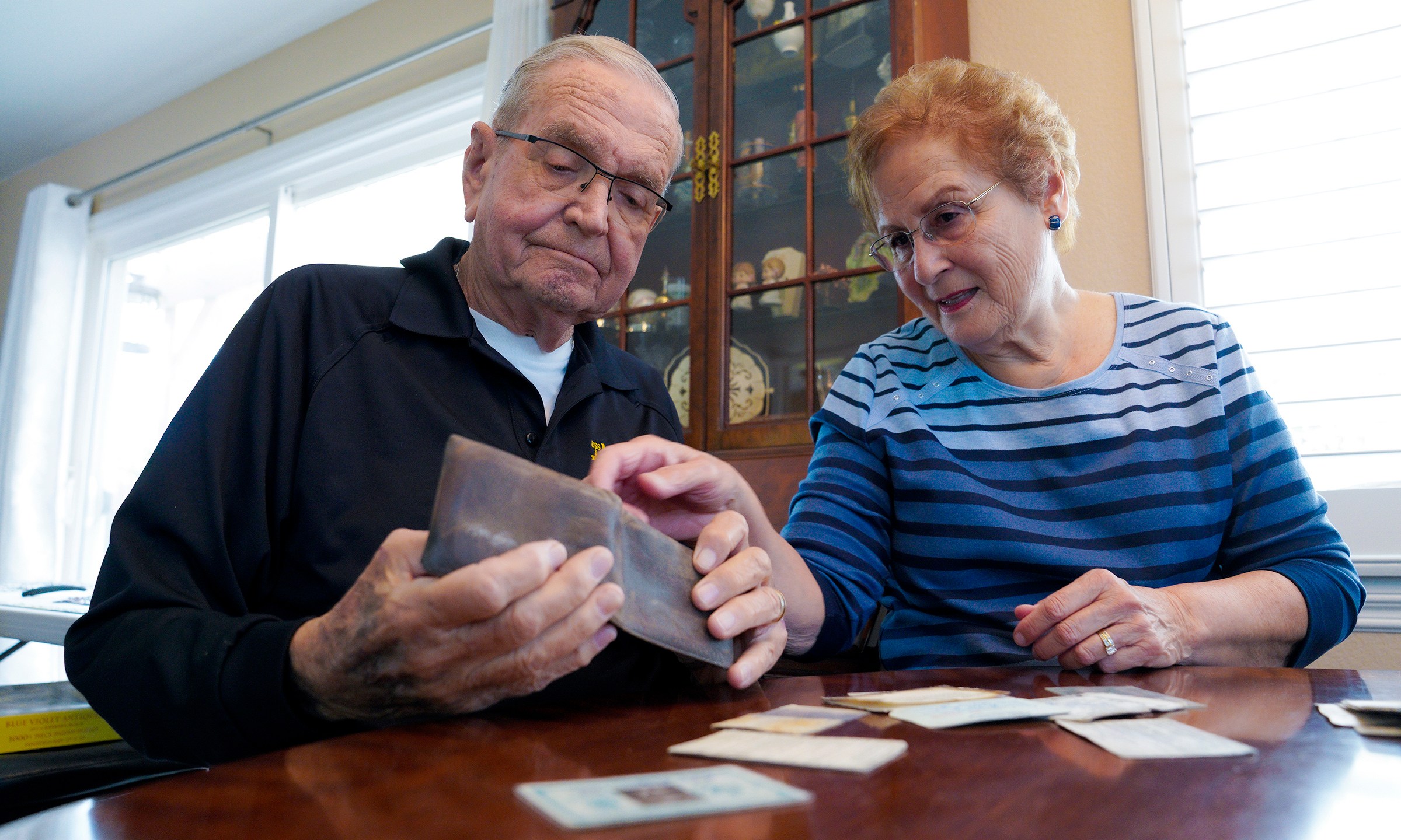 Paul Grisham and his wife Carole Salazar look over his wallet and the items that were inside when he lost the wallet back in 1968 at their home in the San Carlos section of San Diego, Calif., Wednesday, Feb. 3, 2021. Grisham’s wallet was missing for so long he forgot all about it. Fifty-three years later, the 91-year-old has the billfold back along with mementos of his 13-month assignment as a Navy meteorologist on Antarctica in the 1960s. (Nelvin C. Cepeda/The San Diego Union-Tribune via AP)