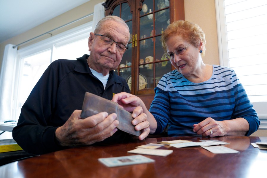 Paul Grisham and his wife Carole Salazar look over his wallet and the items that were inside when he lost the wallet back in 1968 at their home in the San Carlos section of San Diego, Calif., Wednesday, Feb. 3, 2021. Grisham’s wallet was missing for so long he forgot all about it. Fifty-three years later, the 91-year-old has the billfold back along with mementos of his 13-month assignment as a Navy meteorologist on Antarctica in the 1960s. (Nelvin C. Cepeda/The San Diego Union-Tribune via AP)