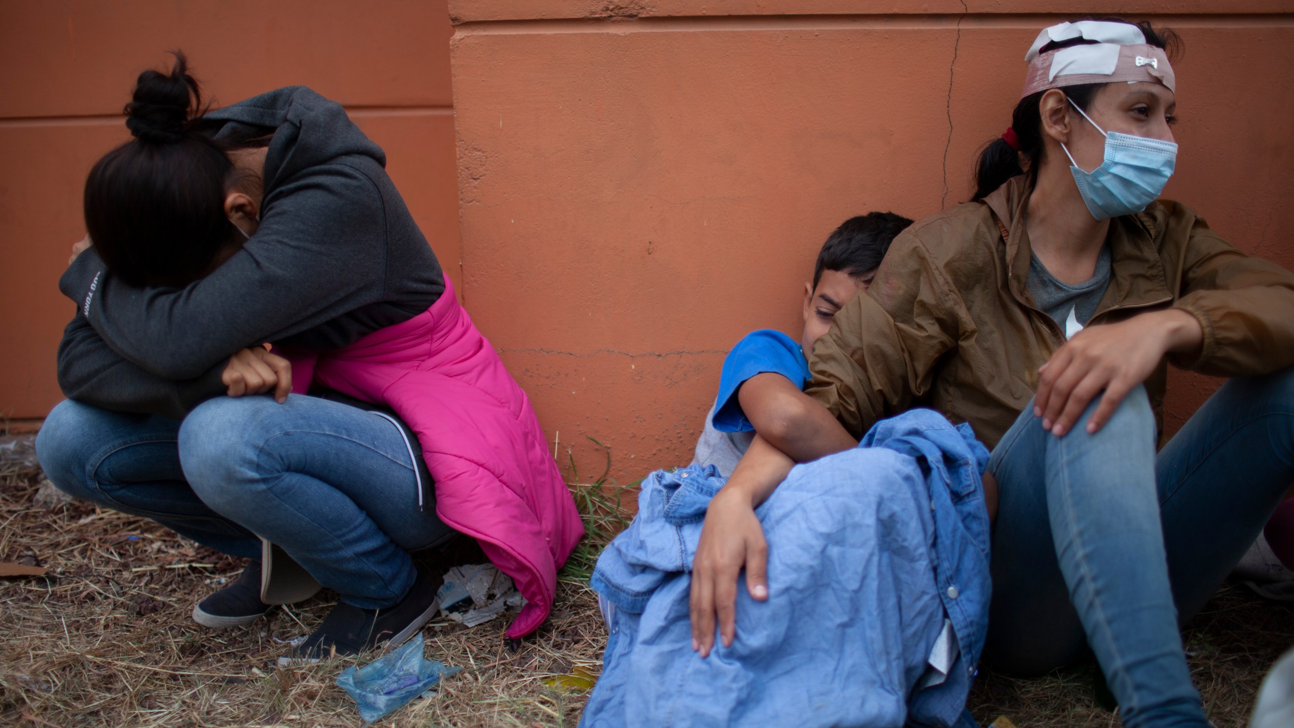 In this Jan. 17, 2021, file photo injured women, part of a Honduran migrant caravan in their bid to reach the U.S. border, weep as they sit on the side of a highway after clashing with Guatemalan police and soldiers in Vado Hondo, Guatemala, Guatemala. (AP Photo/Sandra Sebastian)