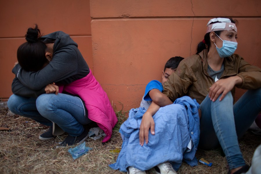 In this Jan. 17, 2021, file photo injured women, part of a Honduran migrant caravan in their bid to reach the U.S. border, weep as they sit on the side of a highway after clashing with Guatemalan police and soldiers in Vado Hondo, Guatemala, Guatemala. (AP Photo/Sandra Sebastian)