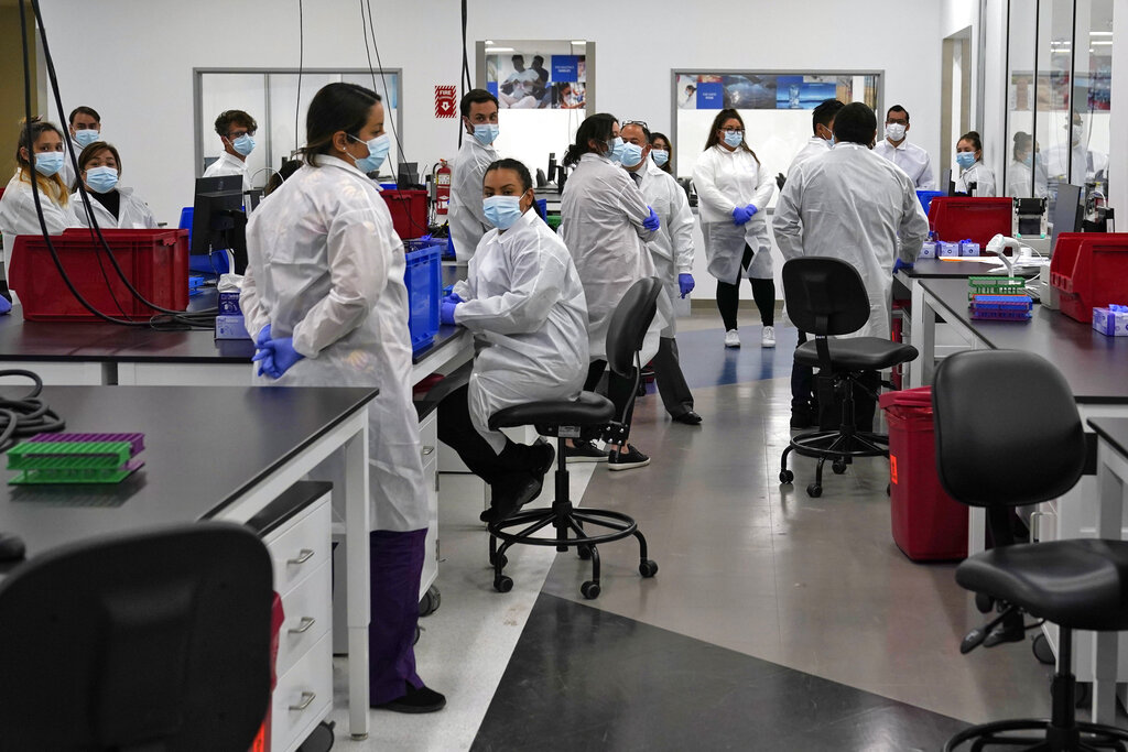 In this Oct. 30, 2020 file photo Lab technicians huddle at a COVID-19 testing facility, in Valencia.(AP Photo/Marcio Jose Sanchez, Pool,File)