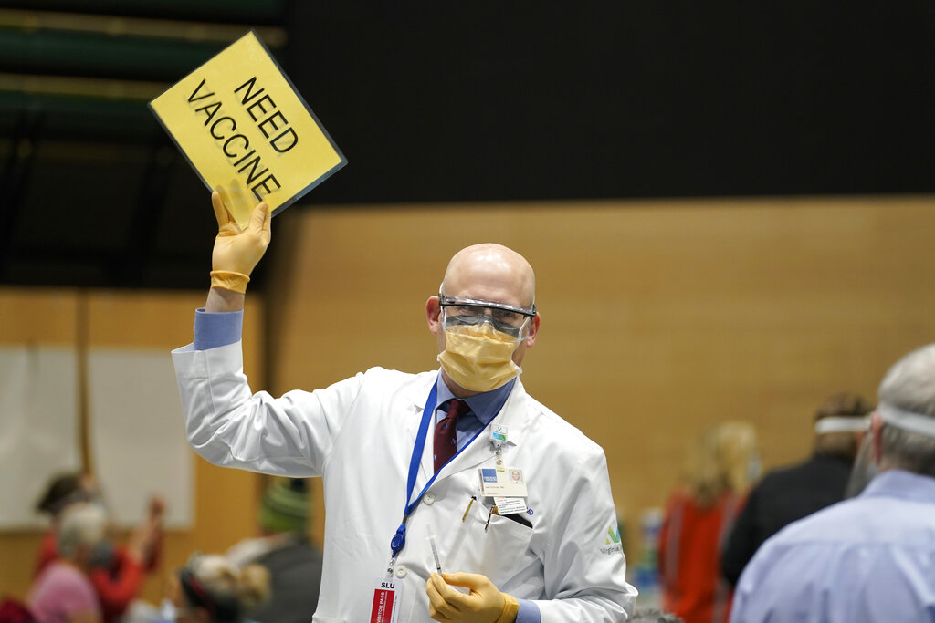 In this Jan. 24, 2021, file photo, Dr. John Corman, the chief clinical officer for Virginia Mason Franciscan Health, holds a sign that reads "Need Vaccine" to signal workers to bring him more doses of the Pfizer vaccine for COVID-19 in Seattle. (AP Photo/Ted S. Warren, File)