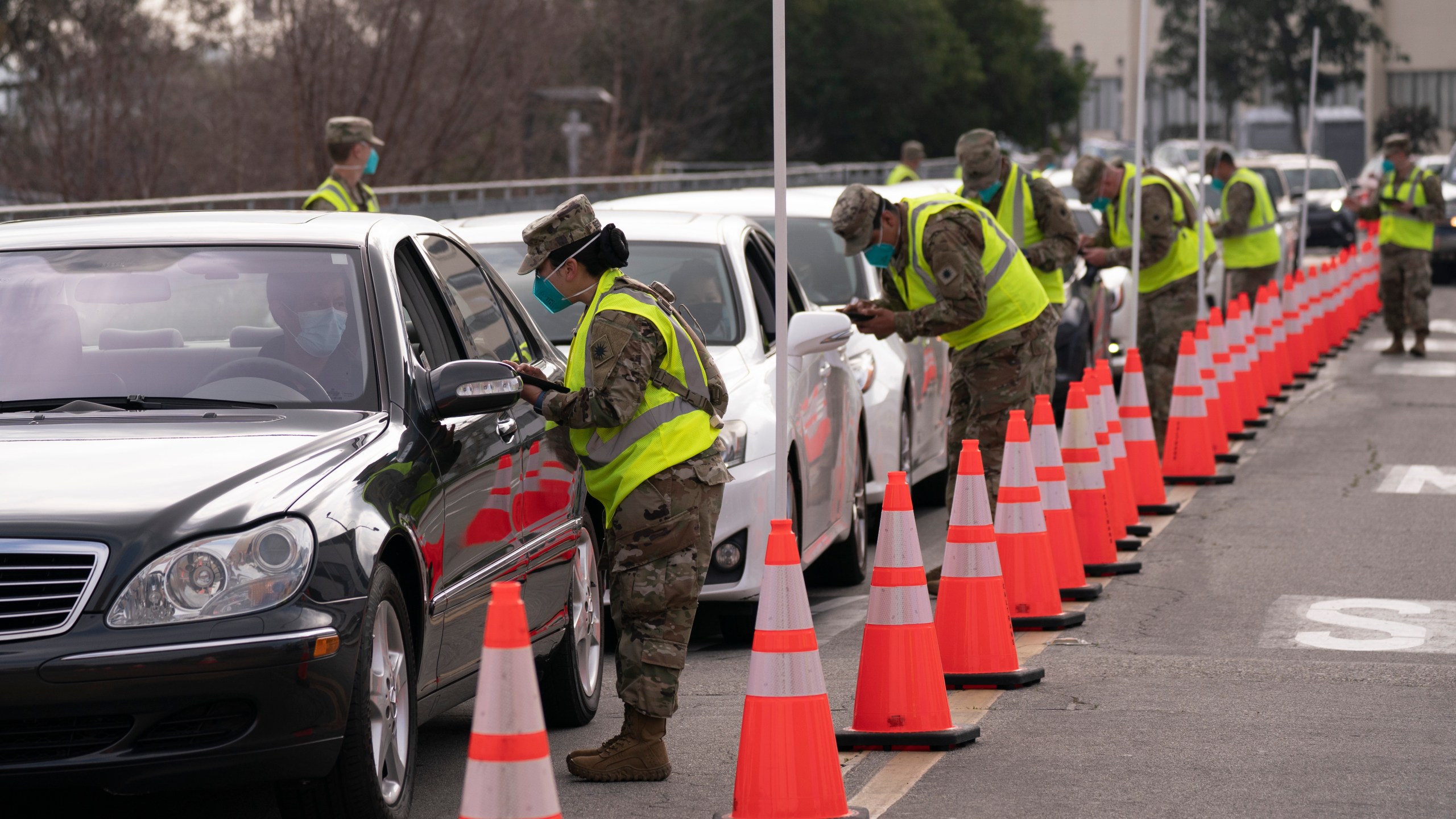 Members of the National Guard help motorists check in at a federally-run COVID-19 vaccination site set up on the campus of California State University of Los Angeles on Feb. 16, 2021. (AP Photo/Jae C. Hong)