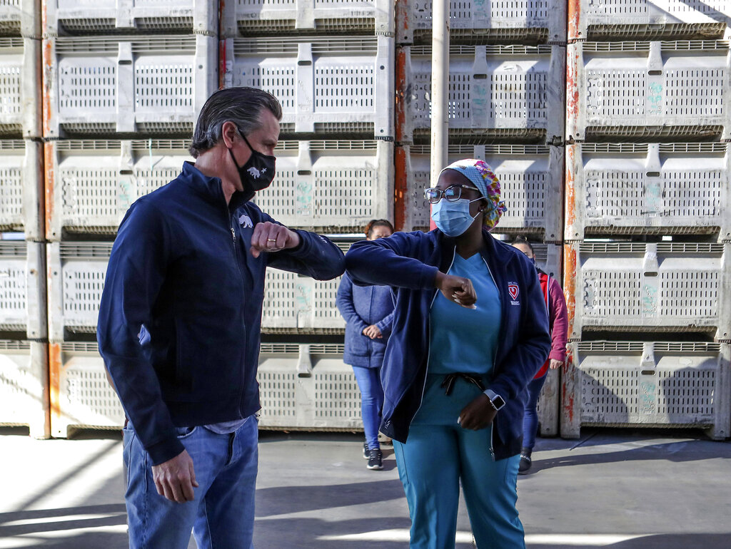 Gov. Gavin Newsom greets registered nurse Arlene Arrechea before holding a news conference in Coachella, Ca., Wednesday, Feb. 17, 2021. (Jay Calderon/The Desert Sun via AP , Pool)