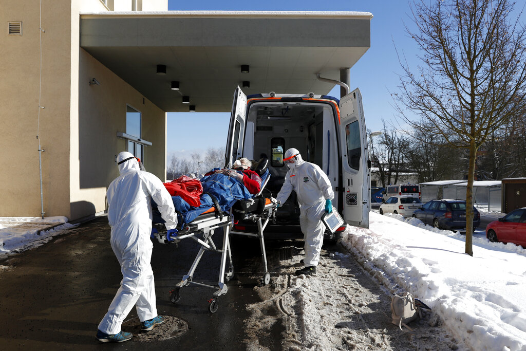 In this Friday, Feb. 12, 2021, file photo, medical workers move a COVID-19 patient into an ambulance at a hospital overrun by the COVID pandemic in Cheb, Czech Republic. (AP Photo/Petr David Josek/File)