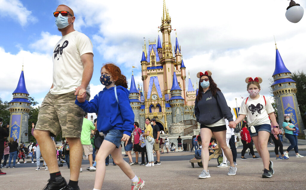 In this Dec. 21, 2020 file photo, A family walks past Cinderella Castle in the Magic Kingdom, at Walt Disney World in Lake Buena Vista, Fla. (Joe Burbank/Orlando Sentinel via AP, File)