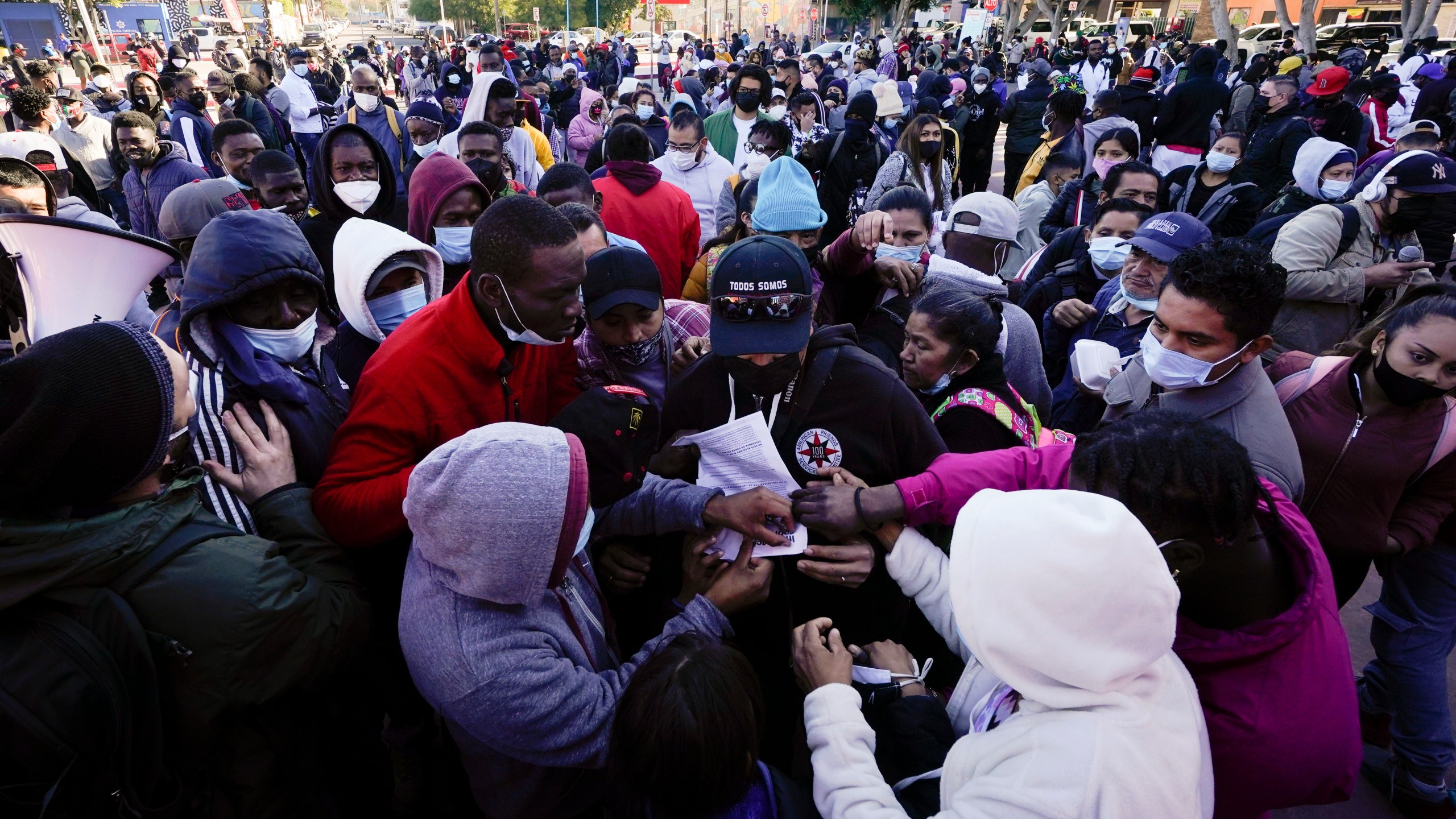 A man tries to hand out flyers explaining policy changes to asylum seekers waiting in Tijuana, Mexico, on Feb. 19, 2021. (Gregory Bull / Associated Press)