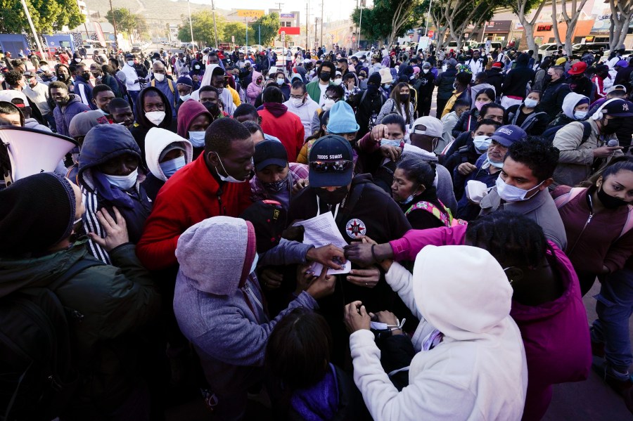 A man tries to hand out flyers explaining policy changes to asylum seekers waiting in Tijuana, Mexico, on Feb. 19, 2021. (Gregory Bull / Associated Press)