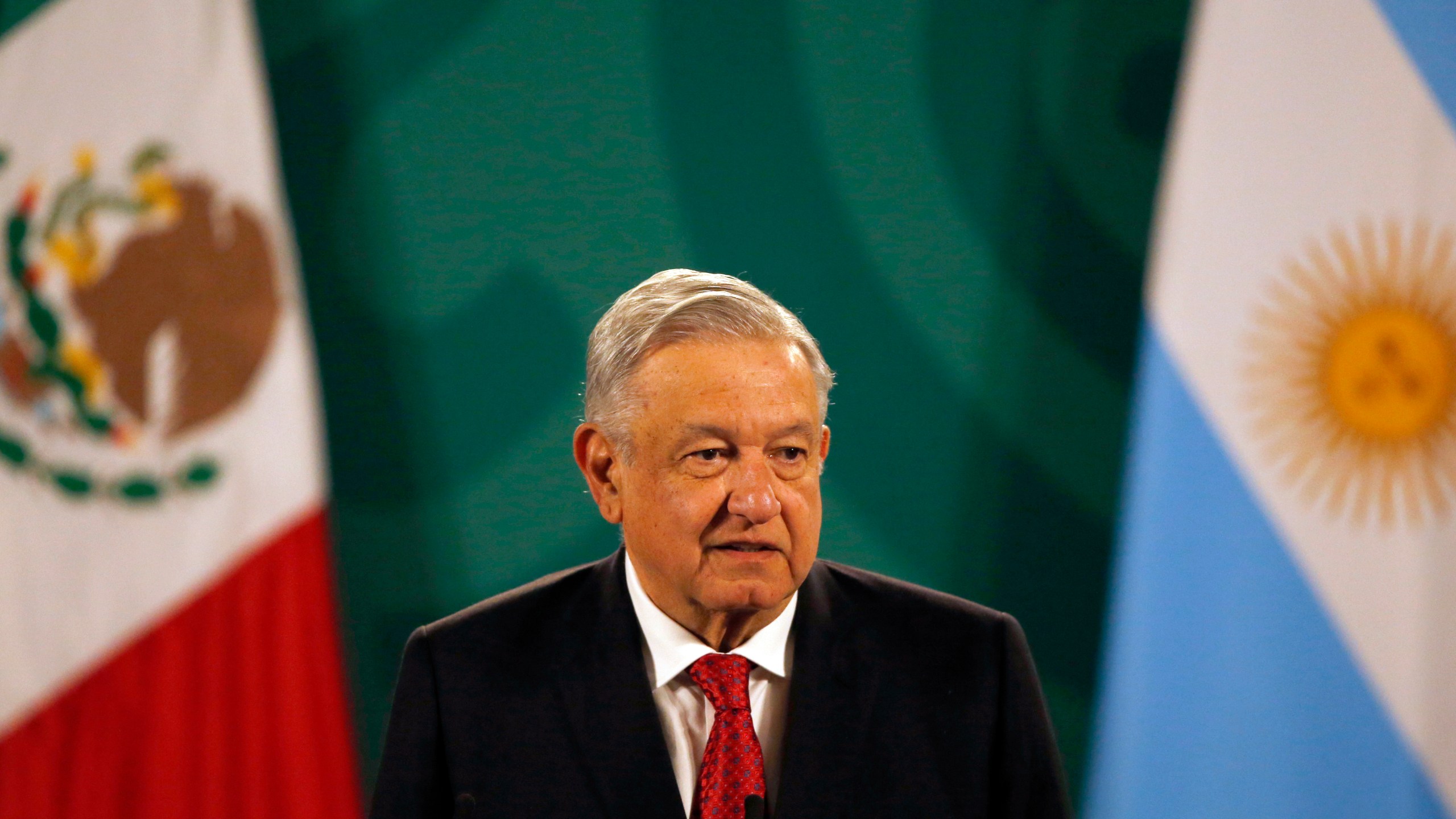 Mexican President Andrés Manuel López Obrador gives his daily, morning press conference at the National Palace in Mexico City, Tuesday, Feb. 23, 2021, with an Argentine flag in the background, right, as Argentine President Alberto Fernandez attends the event. (AP Photo/Marco Ugarte)