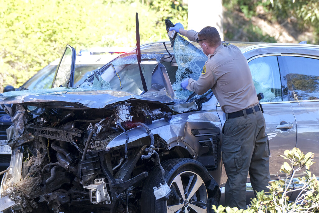 A law enforcement officer looks over a damaged vehicle following a rollover accident involving golfer Tiger Woods, Tuesday, Feb. 23, 2021, in the Rancho Palos Verdes suburb of Los Angeles.(AP Photo/Ringo H.W. Chiu)