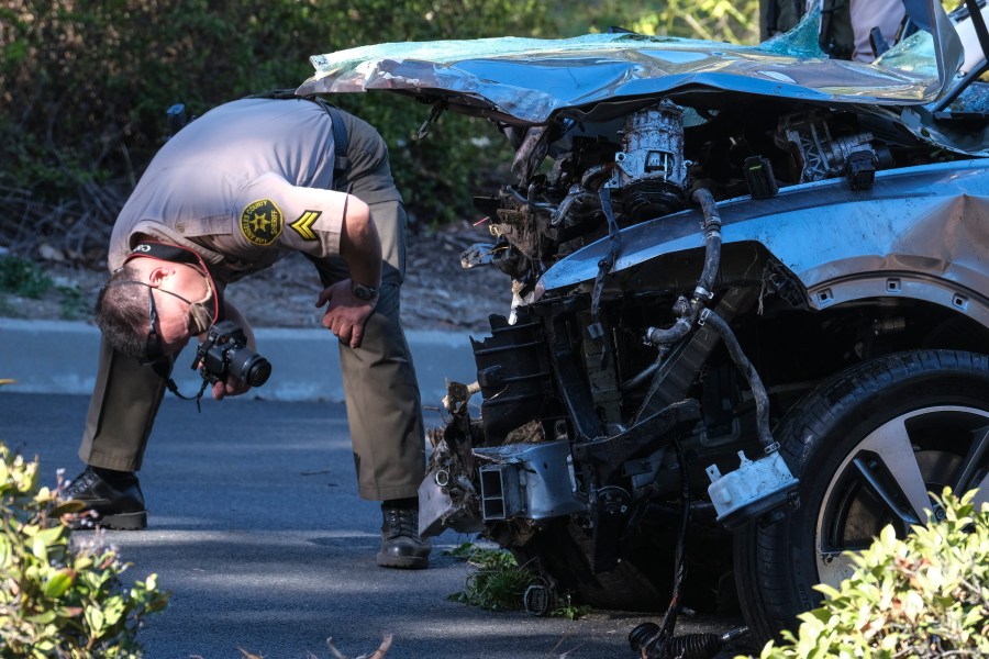 A law enforcement officer looks over a damaged vehicle following a rollover accident involving golfer Tiger Woods on Feb. 23, 2021, in the Rancho Palos Verdes suburb of Los Angeles. (Ringo H.W. Chiu / Associated Press)