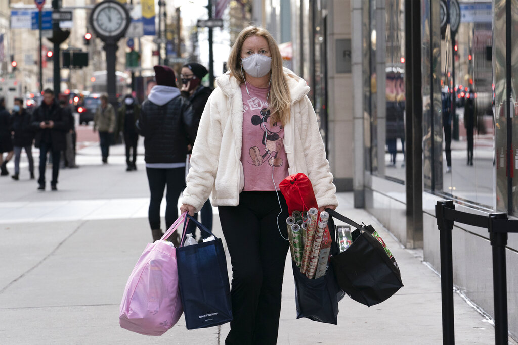 In this Dec. 10, 2020 file photo, a woman carries shopping bags in New York. (AP Photo/Mark Lennihan, File)