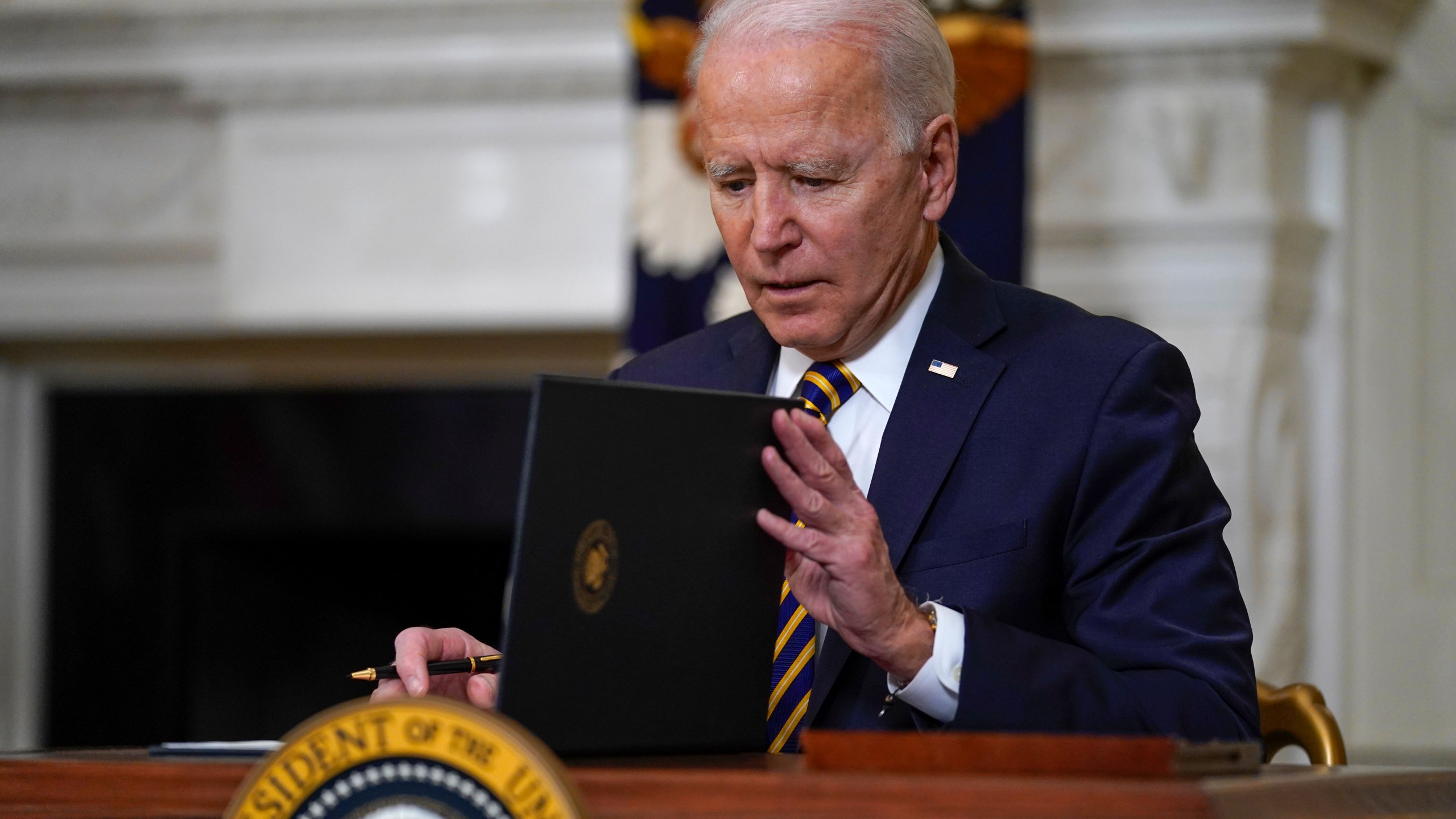 President Joe Biden closes the folder after signing an executive order relating to U.S. supply chains, in the State Dining Room of the White House on Feb. 24, 2021. (Evan Vucci / Associated Press)