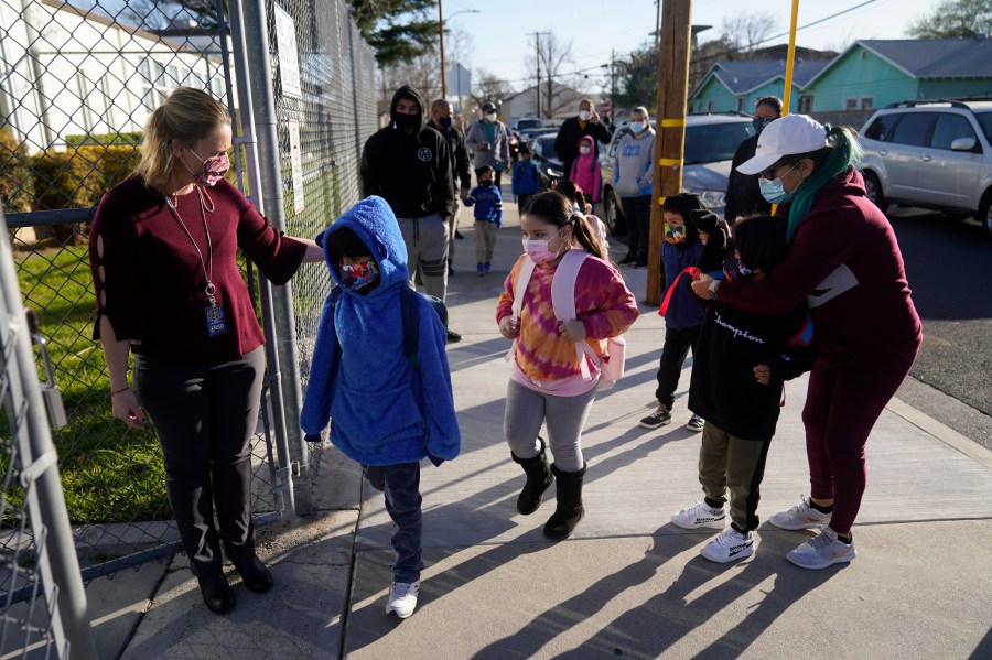 Assistant Principal Janette Van Gelderen, left, welcomes students at Newhall Elementary School in Santa Clarita on Feb. 25, 2021. Elementary school students returned to school this week in the Newhall School District. (Marcio Jose Sanchez / Associated Press)