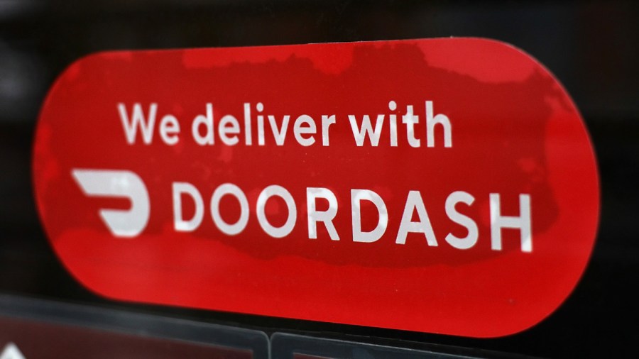 A Doordash sticker is seen on a window of a restaurant. (Photo by Michael M. Santiago/Getty Images)