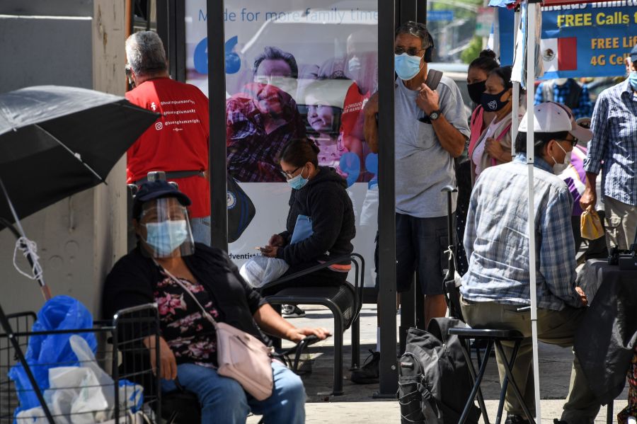 People wait for a bus in a neighborhood of East Los Angeles, Aug. 7, 2020 in Los Angeles, California during the coronavirus pandemic. (Robyn Beck/AFP via Getty Images)