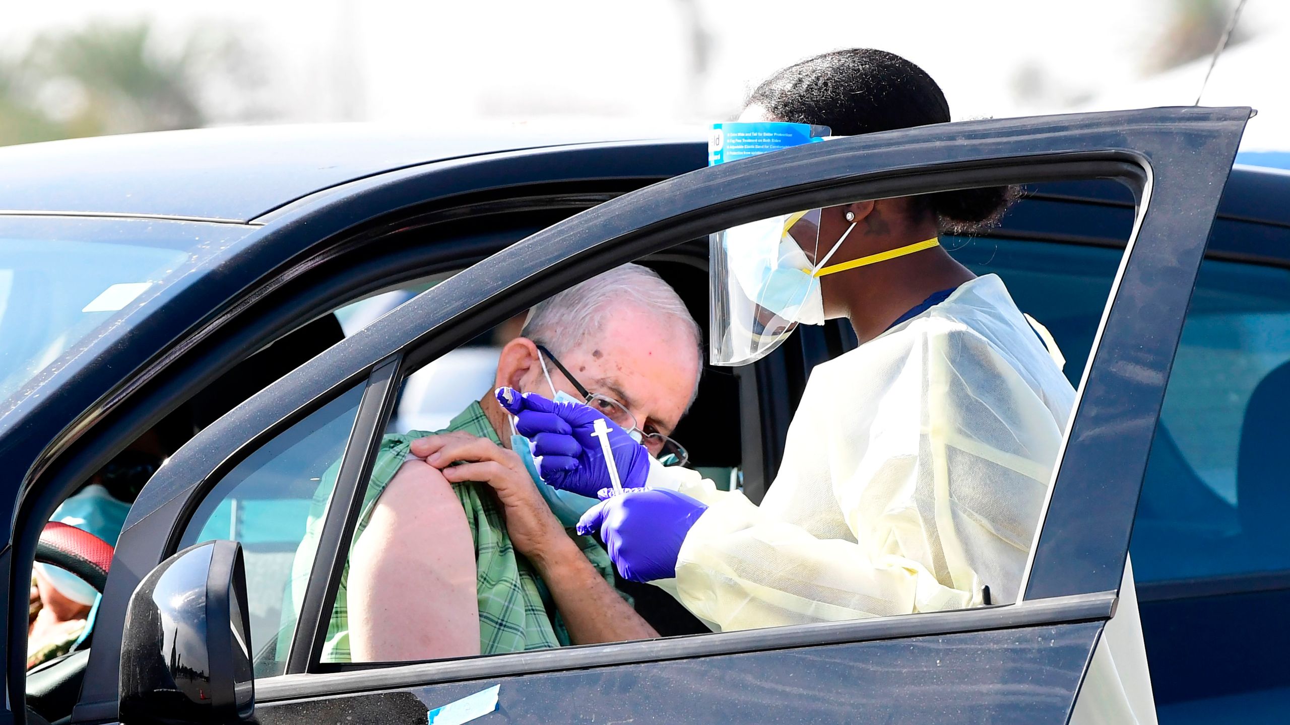 People pull up in their vehicles for Covid-19 vaccines in the parking lot of The Forum in Inglewood, California on Jan. 19, 2021. (FREDERIC J. BROWN/AFP via Getty Images)