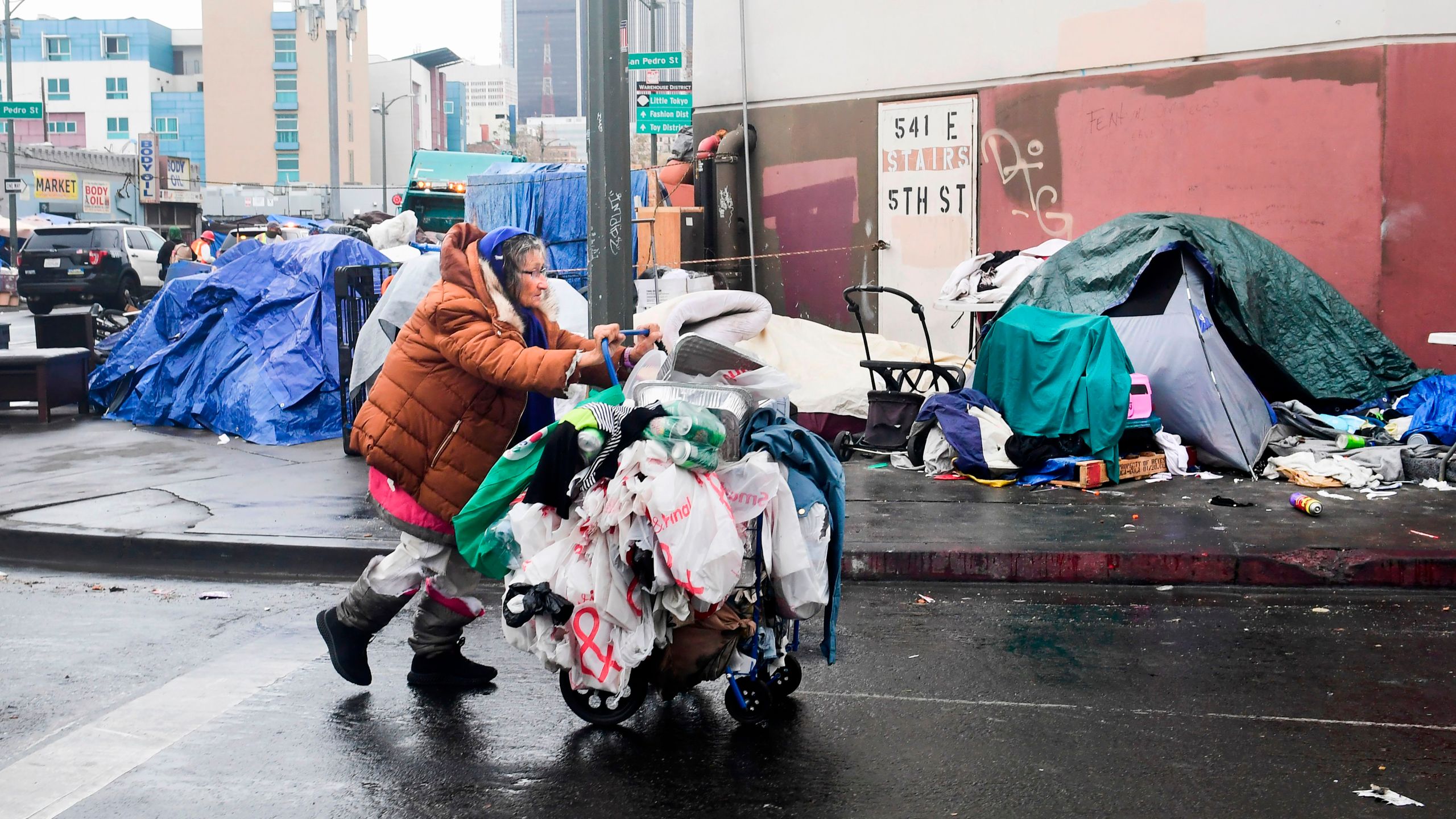 A homeless woman pushes her belongings past a row of tents on the streets of Los Angeles on Feb. 1, 2021. (Frederic J. Brown / AFP / Getty Images)