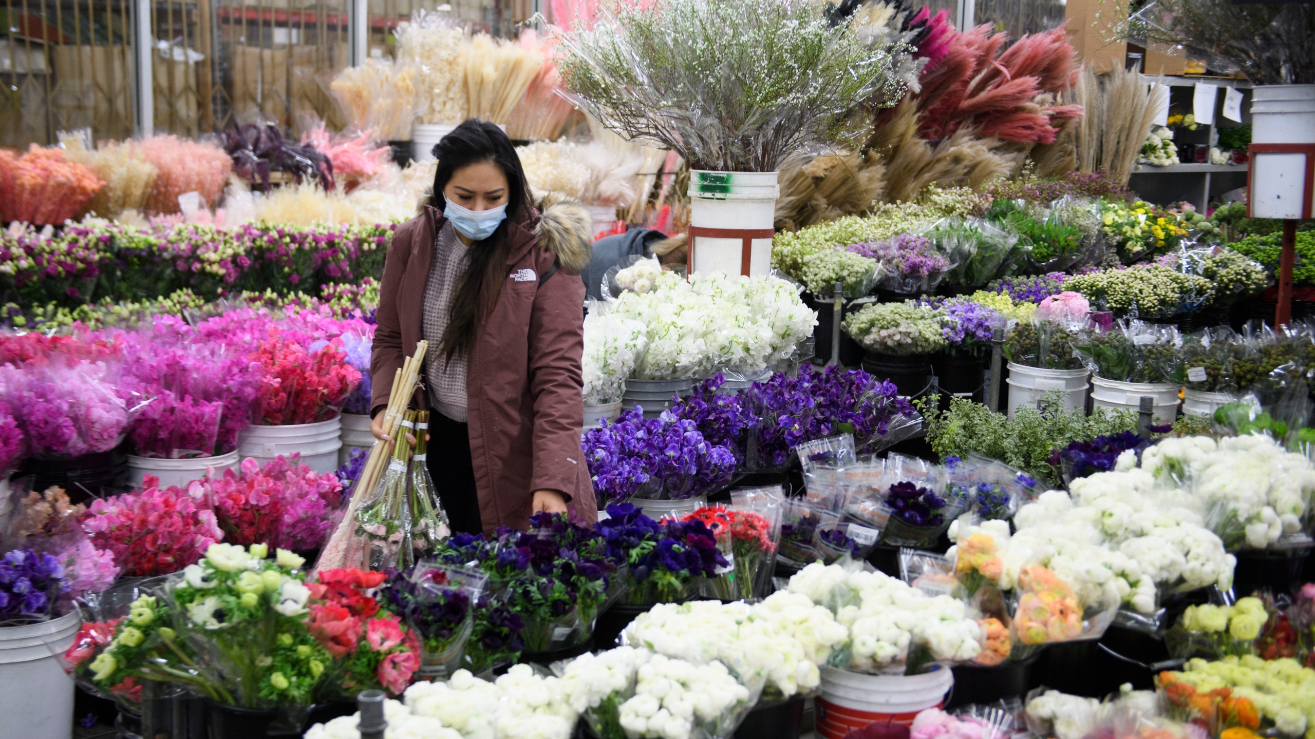 A customer wears a face mask while shopping for flowers displayed for sale from a wholesale merchant ahead of the Valentine's Day holiday at the Southern California Flower Market on Feb. 12, 2021 in Los Angeles. (PATRICK T. FALLON/AFP via Getty Images)