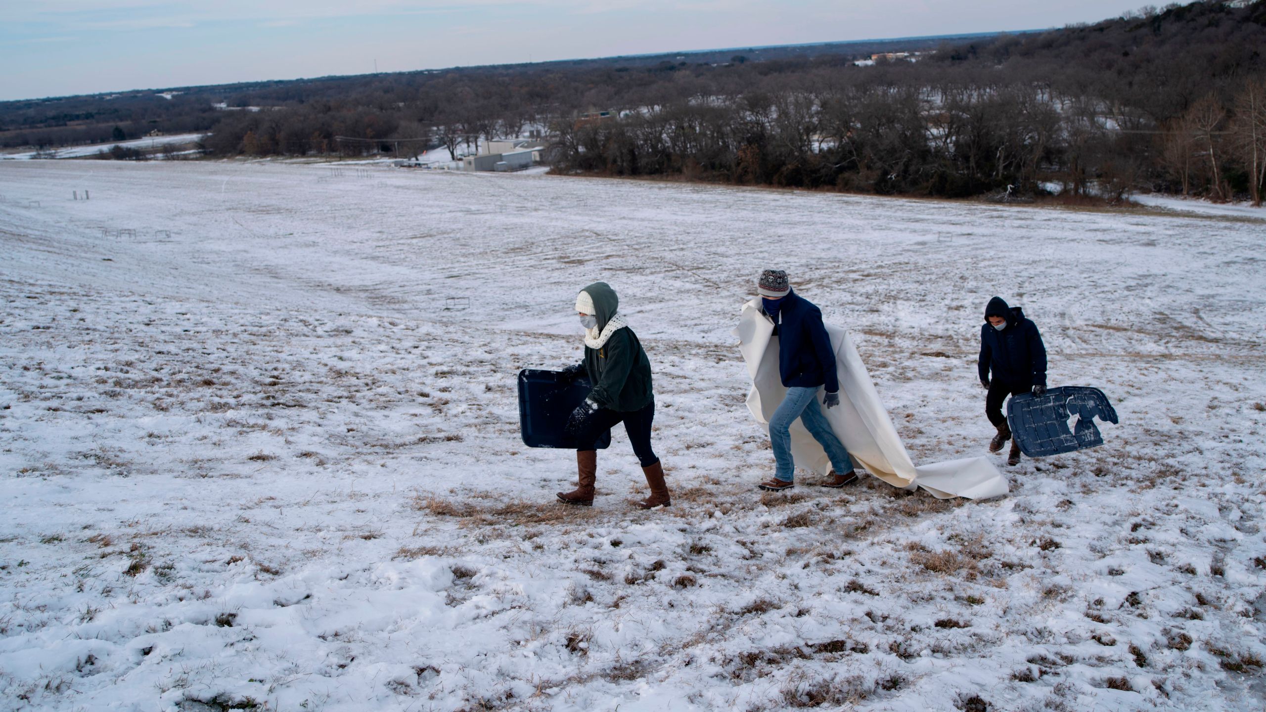 Connie Mendoza, Alberto Torres and Jazy Mendoza climb up a steep hill next to Lake Waco dam in Waco, Texas on Thursday, Feb. 18, 2021. (MATTHEW BUSCH/AFP via Getty Images)