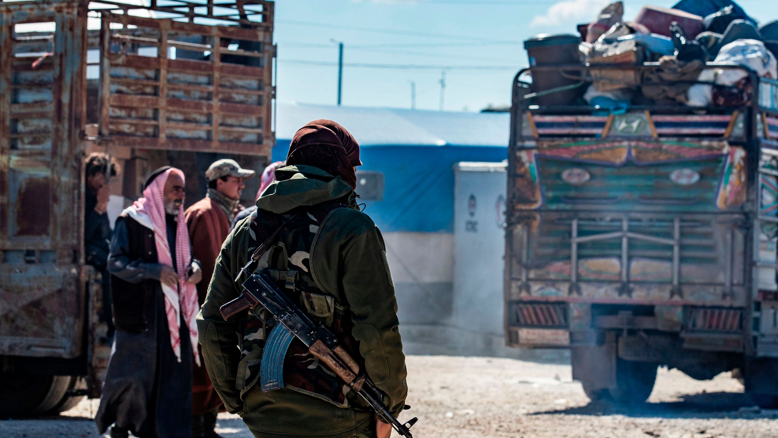 A member of Kurdish internal security stands guard during the release of another group of Syrian families from the Kurdish-run al-Hol camp which holds suspected relatives of Islamic State (IS) group fighters, in Hasakeh governorate of northeastern Syria, on Feb. 20, 2021. (Delil SOULEIMAN / AFP via Getty Images)