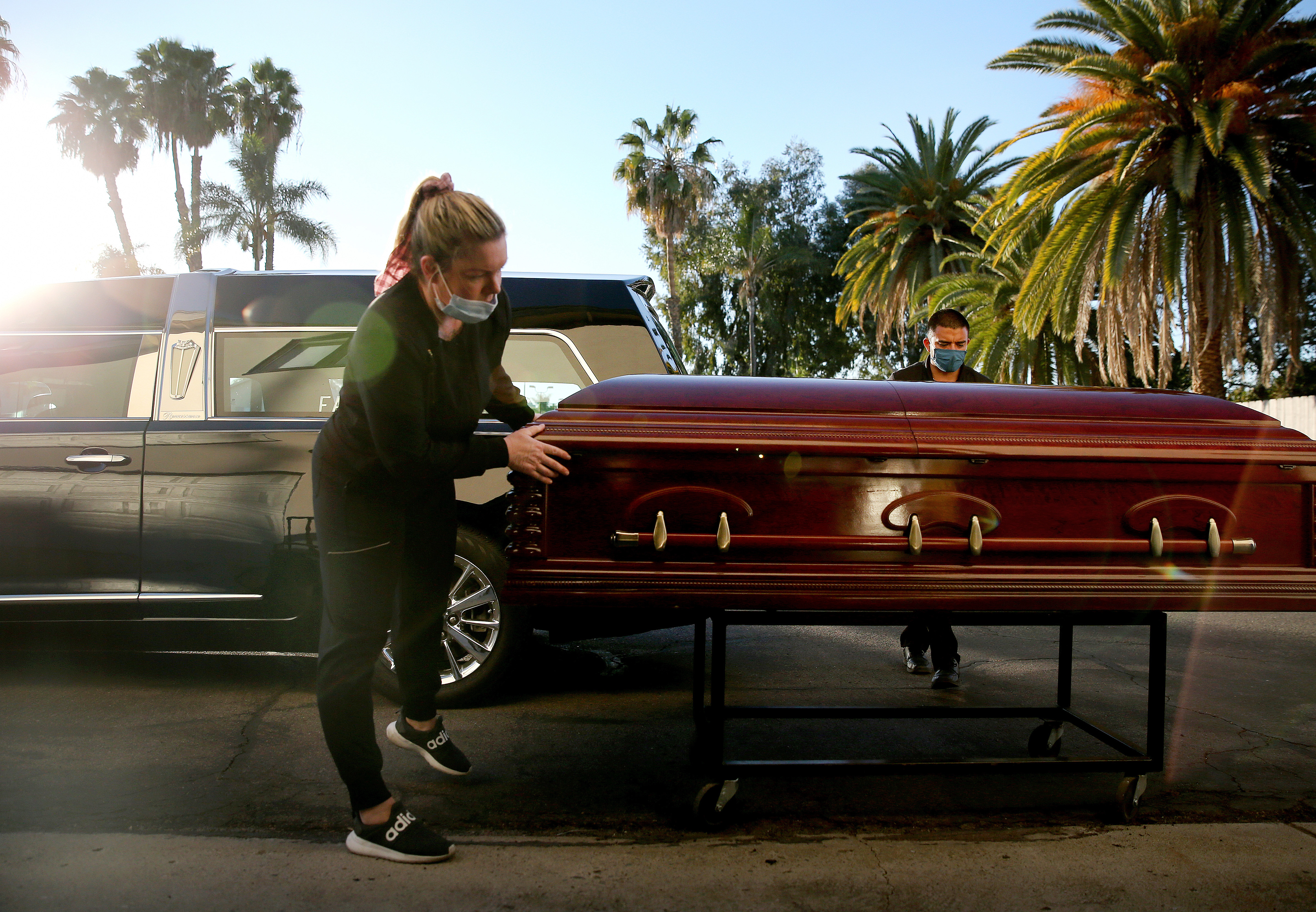 Embalmer and funeral director Kristy Oliver and funeral attendant Sam Deras prepare to load the casket of a person who died after contracting the coronavirus into a hearse at East County Mortuary on Jan. 15, 2021 in El Cajon. (Mario Tama/Getty Images)