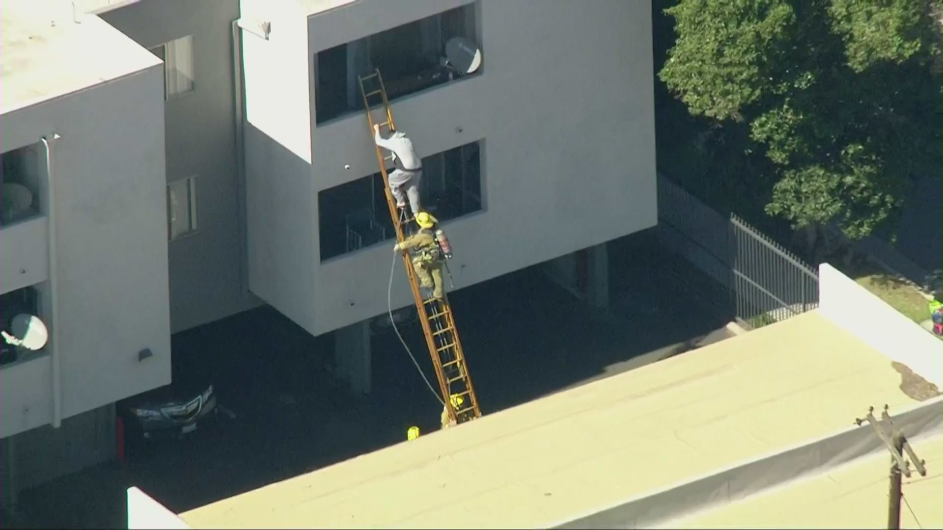 A firefighter helps a man escape an apartment building fire in Northridge on Feb. 18, 2021. (KTLA)