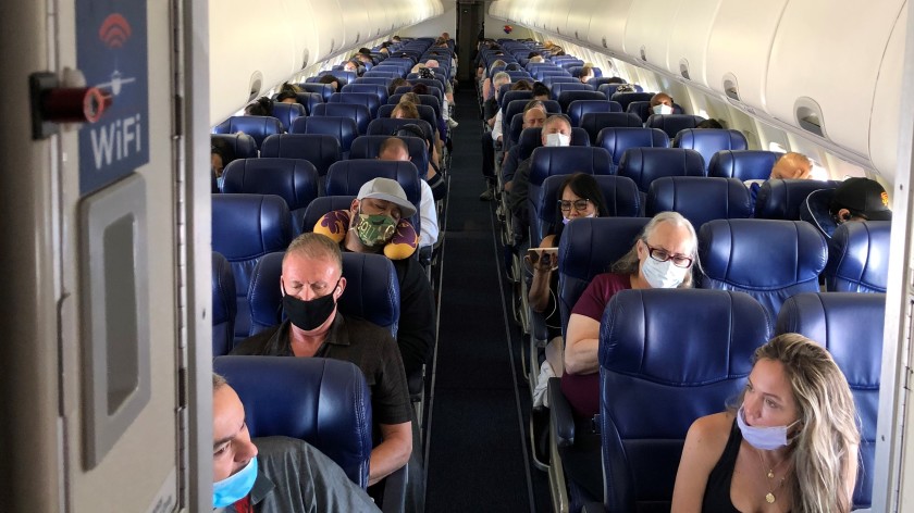 Passengers wear masks — some with their noses peeking out — on a June 3 flight. Under CDC guidelines, masks must completely cover the wearer’s nose and mouth. (Christopher Reynolds / Los Angeles Times)