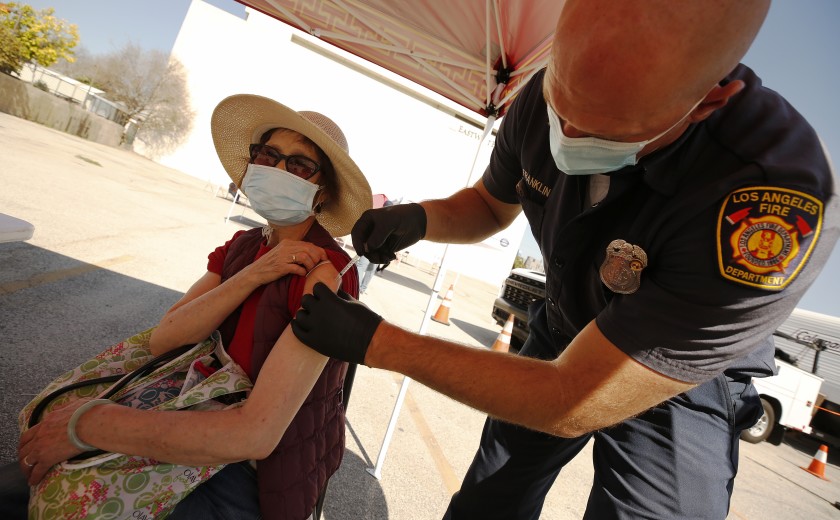 Yuyao Lui, 76, receives a COVID-19 vaccine shot from Joseph Franklin, an L.A. firefighter and paramedic, at a clinic in Chinatown in an undated photo. (Al Seib / Los Angeles Times)