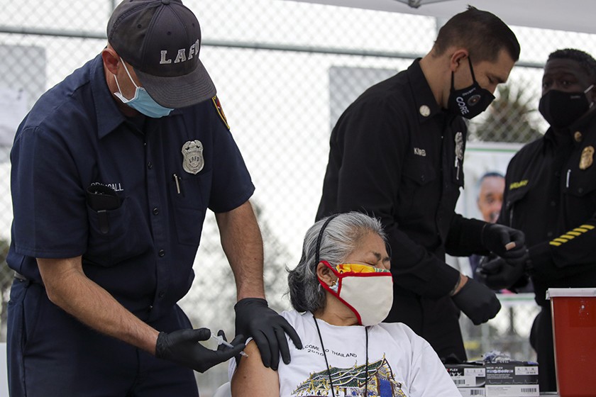 Firefighter Anthony MacDougall administers a COVID-19 vaccine to Carmen Limeta at a mobile vaccination site at South Park Recreation Center in Los Angeles.(Irfan Khan / Los Angeles Times)