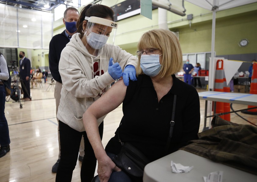 Pacoima Middle School teacher Abigail Abbott, 65, gets her COVID-19 shot from nurse practitioner Jiyoun Cho as Los Angeles Unified employees received their first doses of the vaccine. (Al Seib / Los Angeles Times)