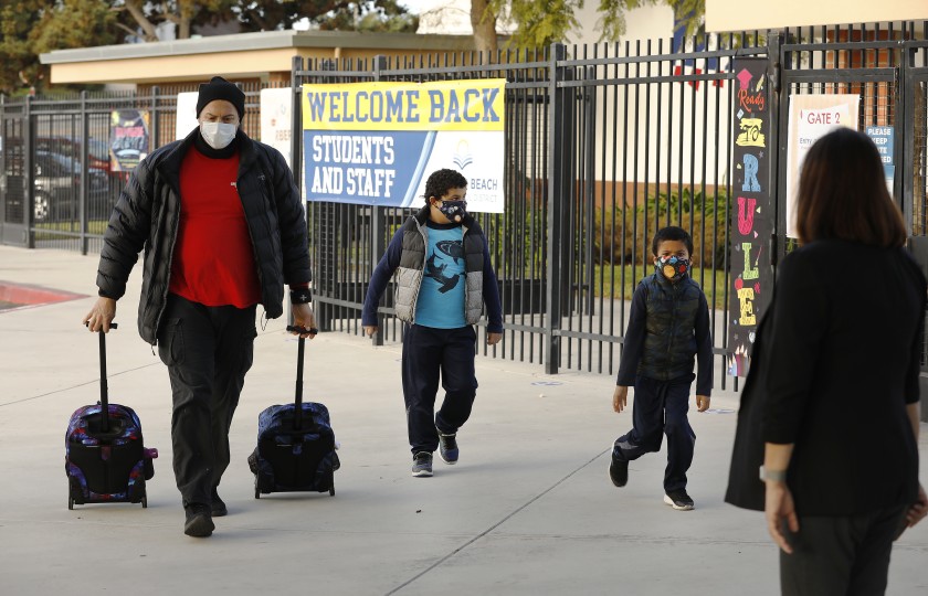 Luis Aracena helps his two children — first grade students Knoah, left, and twin brother Kane — with their backpacks as they arrive at Alta Vista Elementary School in Redondo Beach. (Al Seib / Los Angeles Times)