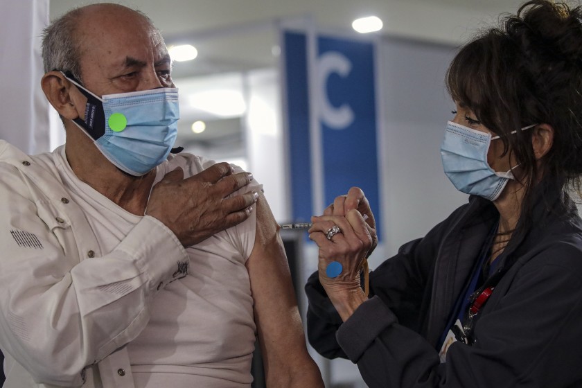 Katharyne Acuna administers the first dose of the Pfizer-BioNTech COVID-19 vaccine to Maximo Michua at a new vaccine center at Cal Poly Pomona on Friday. (Irfan Khan / Los Angeles Times)