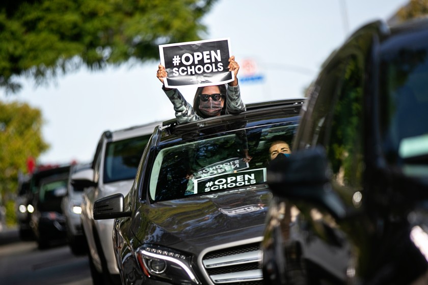 Participants hold signs and honk horns in a car caravan that was part of a Monday event calling for the reopening of K-12 campuses in L..A. County. (Jason Armond / Los Angeles Times)