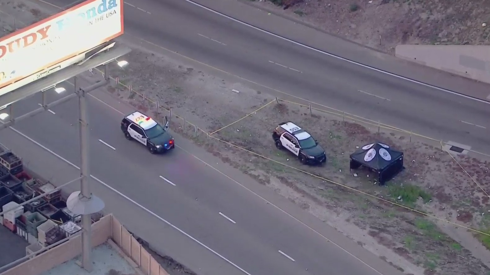 A law enforcement tent sits within the area taped off for investigation after police fatally shot a robbery suspect along the 10 Freeway in El Monte on Feb. 15, 2021. (KTLA)