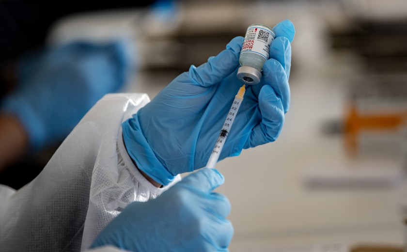 A healthcare professional inserts a syringe into a vial of the Moderna vaccine.(Gina Ferazzi/Los Angeles Times)