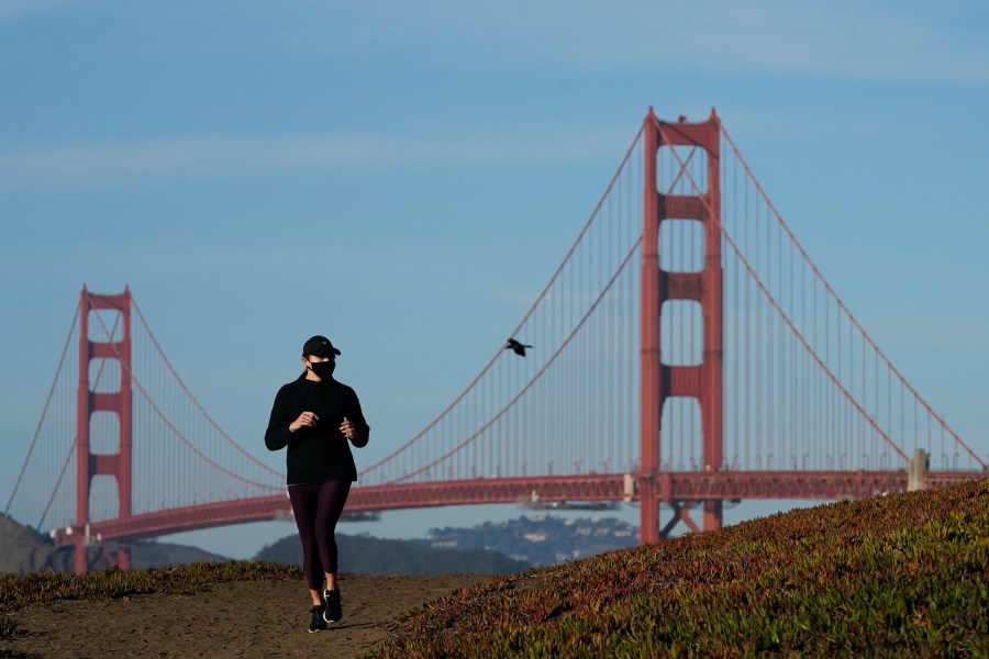 A person wearing a mask runs on a path in front of the Golden Gate Bridge in San Francisco during the coronavirus pandemic on Nov. 30, 2020. (Jeff Chiu / Associated Press)