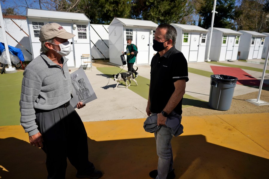 Hope of the Valley CEO Ken Craft, right, talks to resident Ted Beauregard outside of a row of tiny homes for the homeless on Feb. 25, 2021, in North Hollywood. (AP Photo/Marcio Jose Sanchez)