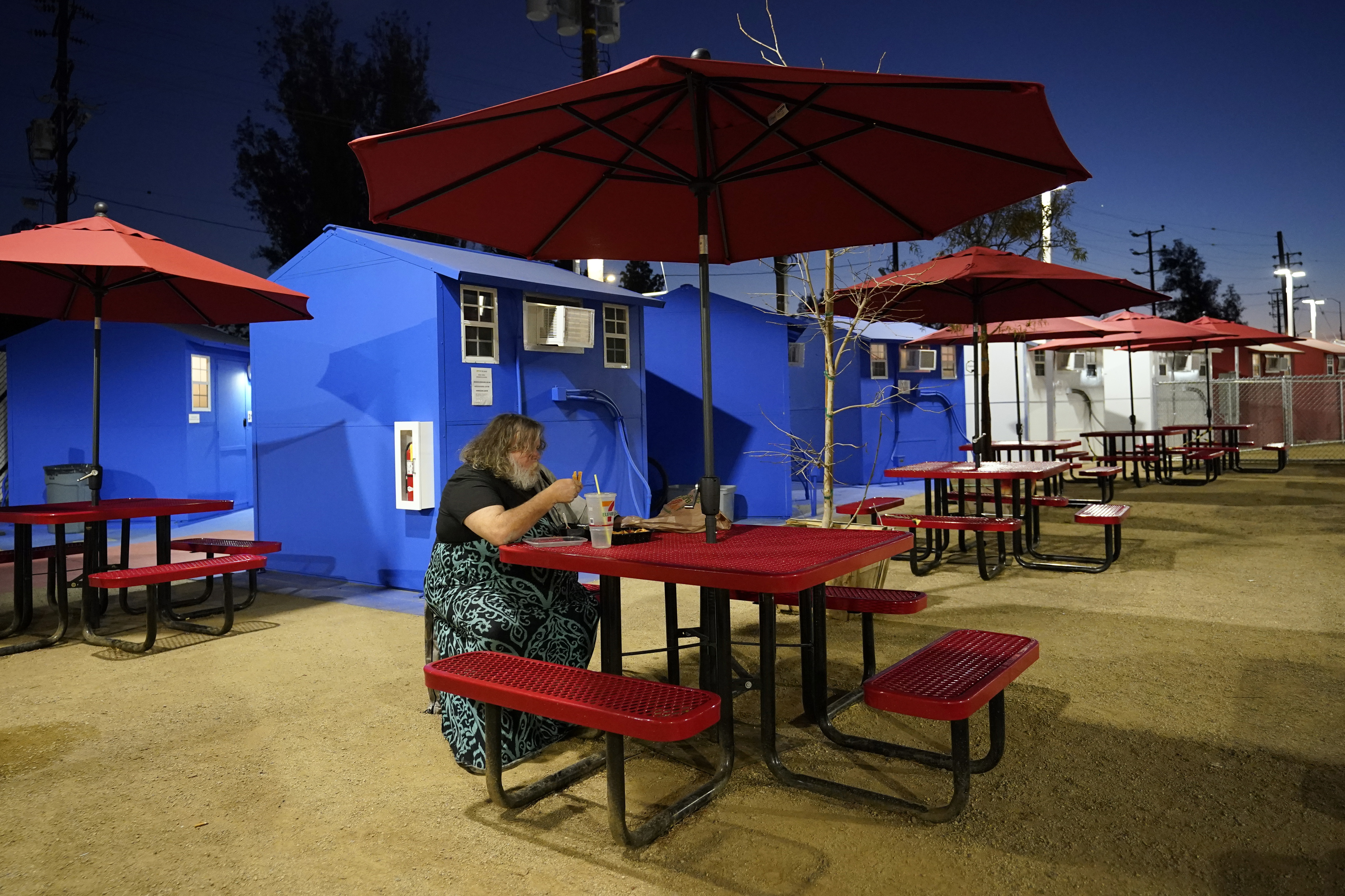 A resident eats in front of a row of tiny homes for the homeless on Feb. 25, 2021, in North Hollywood. (AP Photo/Marcio Jose Sanchez)