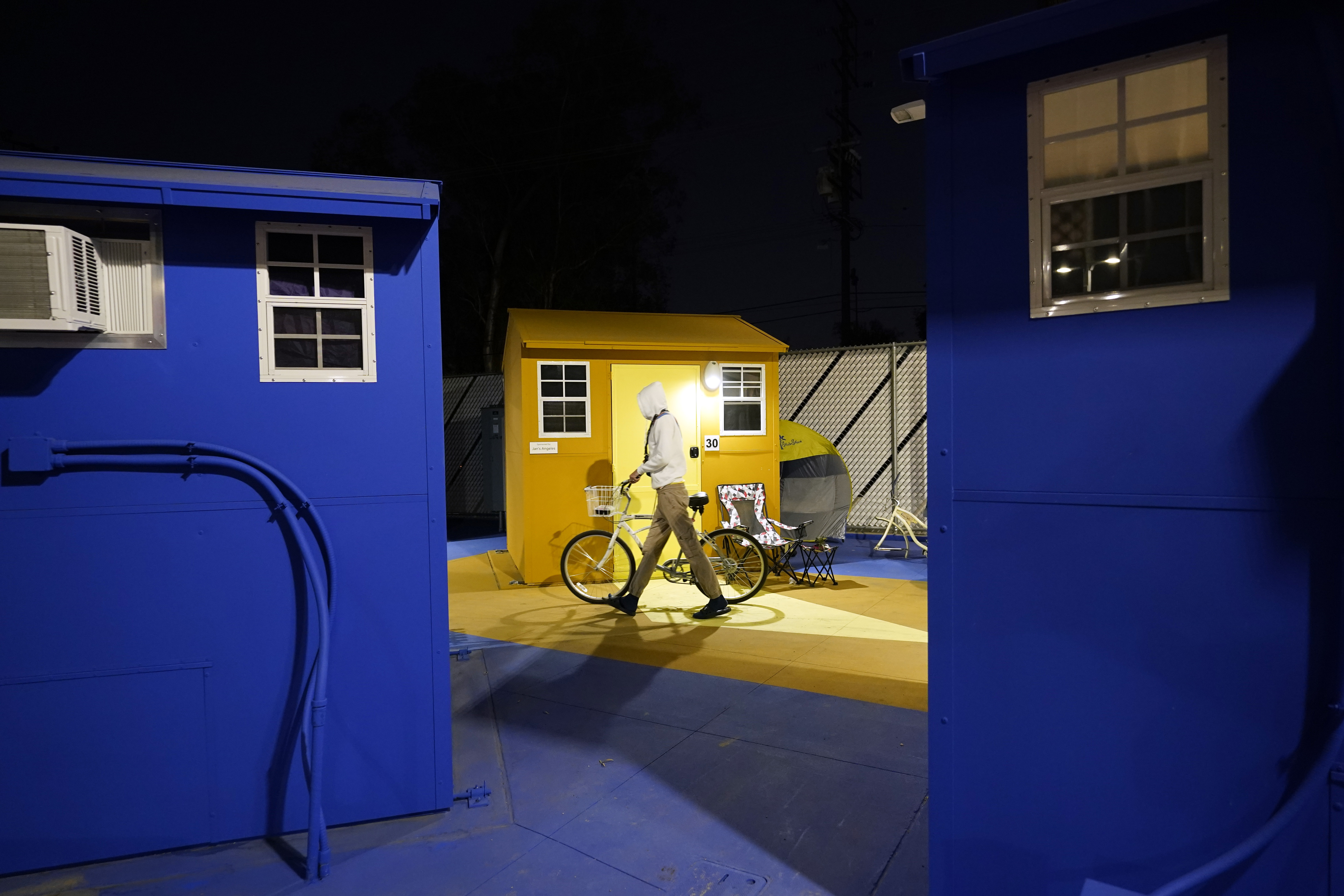 A resident walks with their bike along a row of tiny homes for the homeless on Feb. 25, 2021, in North Hollywood. (AP Photo/Marcio Jose Sanchez)