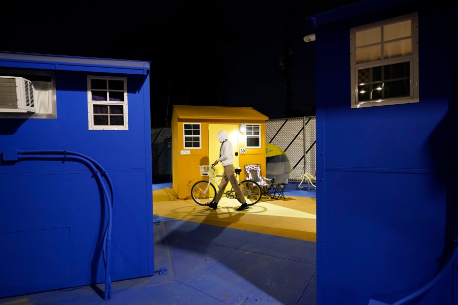 A resident walks with their bike along a row of tiny homes for the homeless on Feb. 25, 2021, in North Hollywood. (AP Photo/Marcio Jose Sanchez)