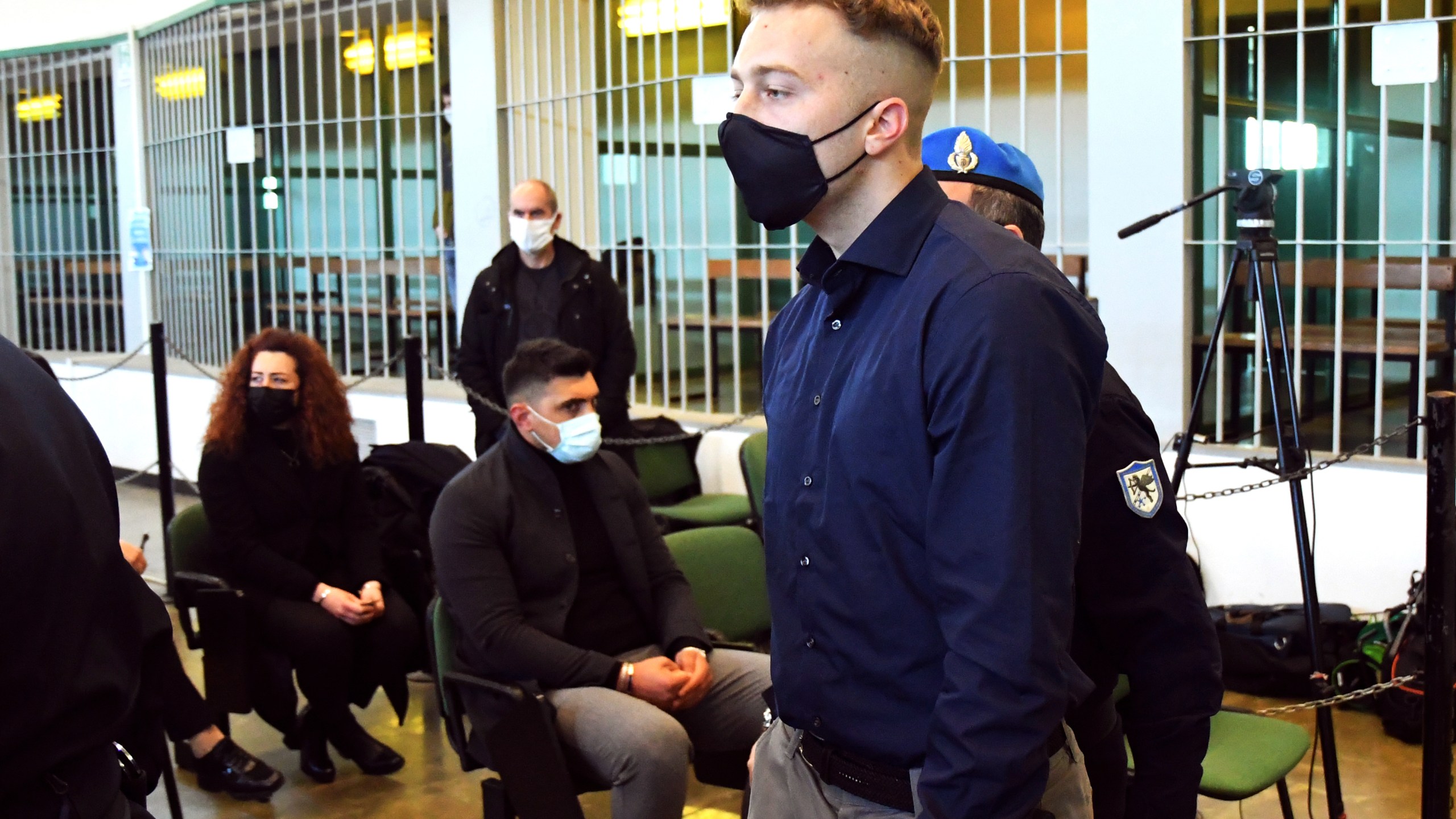 Finnegan Lee Elder, from the United States, walks past to Rosa Maria Esilio, widow of slain Carabinieri military police officer Mario Cerciello Rega, background left, and Paolo Cerciello Rega, brother of Mario, center, on March 1, 2021, prior to a hearing in Rome in the trial where he and Gabriel Natale-Hjorth are accused of slaying a plainclothes Carabinieri officer while on vacation in Italy in July 2019. (Alberto Pizzoli / Associated Press)