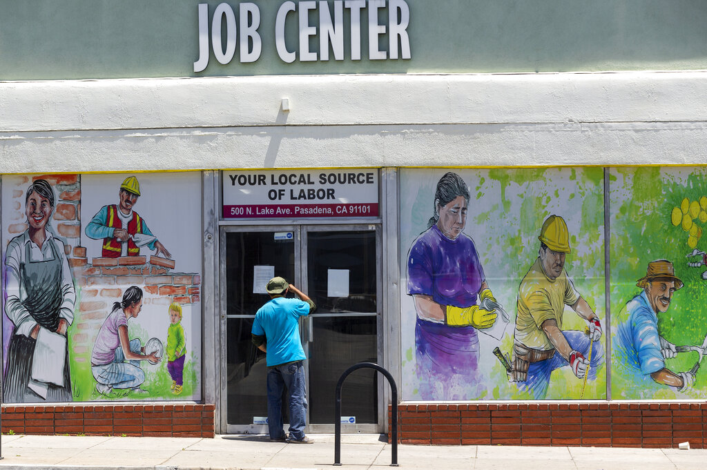 In this May 7, 2020, file photo, a person looks inside the closed doors of the Pasadena Community Job Center in Pasadena. (AP Photo/Damian Dovarganes, File)