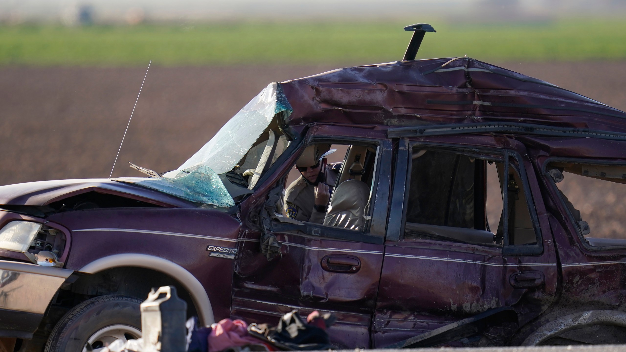 Law enforcement officers sort evidence and debris at the scene of a deadly crash in Holtville, Calif., on Tuesday, March 2, 2021. Authorities say a semi-truck crashed into an SUV carrying 25 people on a Southern California highway, killing at least 13 people. (AP Photo/Gregory Bull)