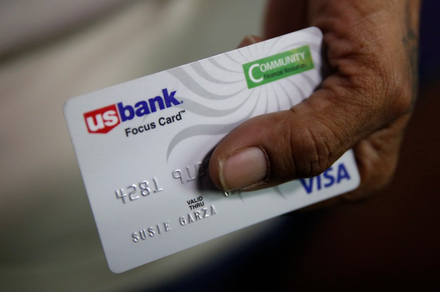 In this Aug. 14, 2019, file photo, Susie Garza displays the city provided debit card she receives monthly through a trial program in Stockton, Calif. A study of people in California who received $500 a month for free says they used it to pay off debt and get full-time jobs. A pair of independent researchers reviewed data from the first year of the study and released their finding on Wednesday, March 3, 2021. (AP Photo/Rich Pedroncelli, File)