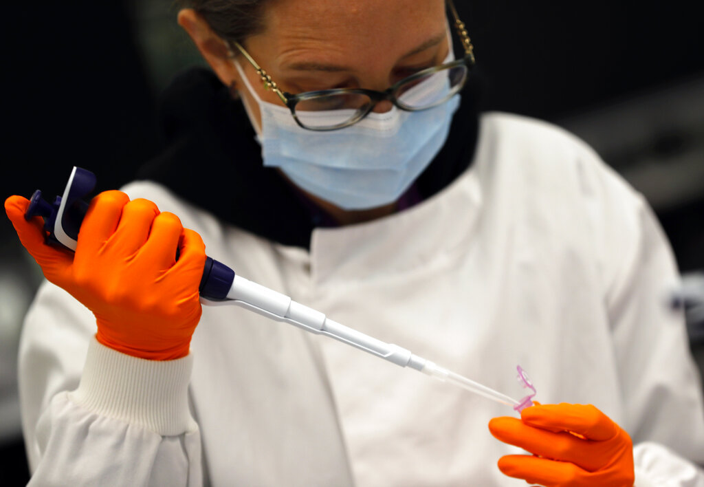 A lab assistant uses a pipette to prepare Coronavirus RNA for sequencing at the Wellcome Sanger Institute that is operated by Genome Research in Cambridge, Thursday, March 4, 2021. (AP Photo/Frank Augstein)