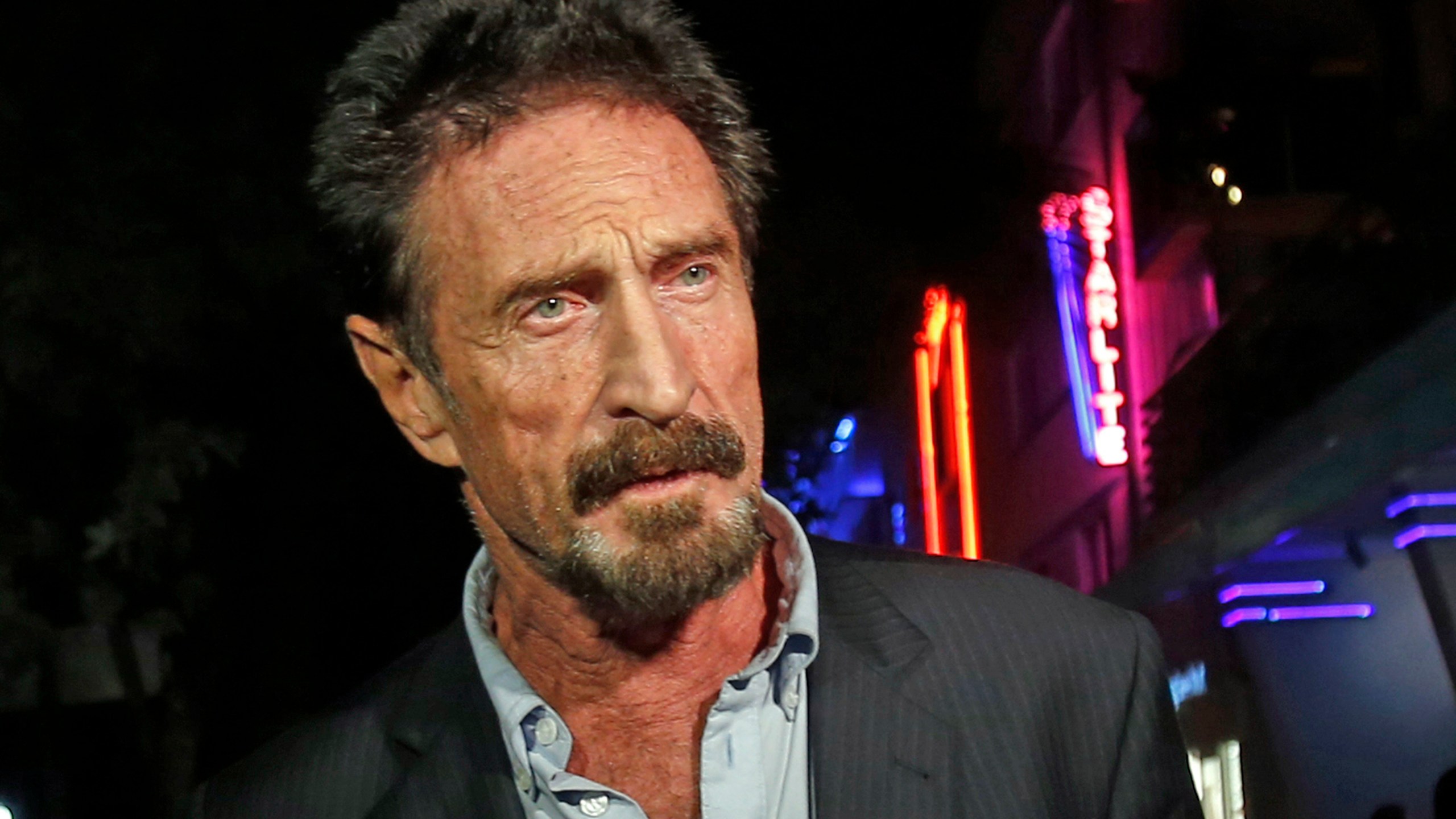 In this Dec. 12, 2012 file photo, anti-virus software founder John McAfee answers questions to reporters as he walks on Ocean Drive, in the South Beach area of Miami Beach, Fla. (AP Photo/Alan Diaz, File)